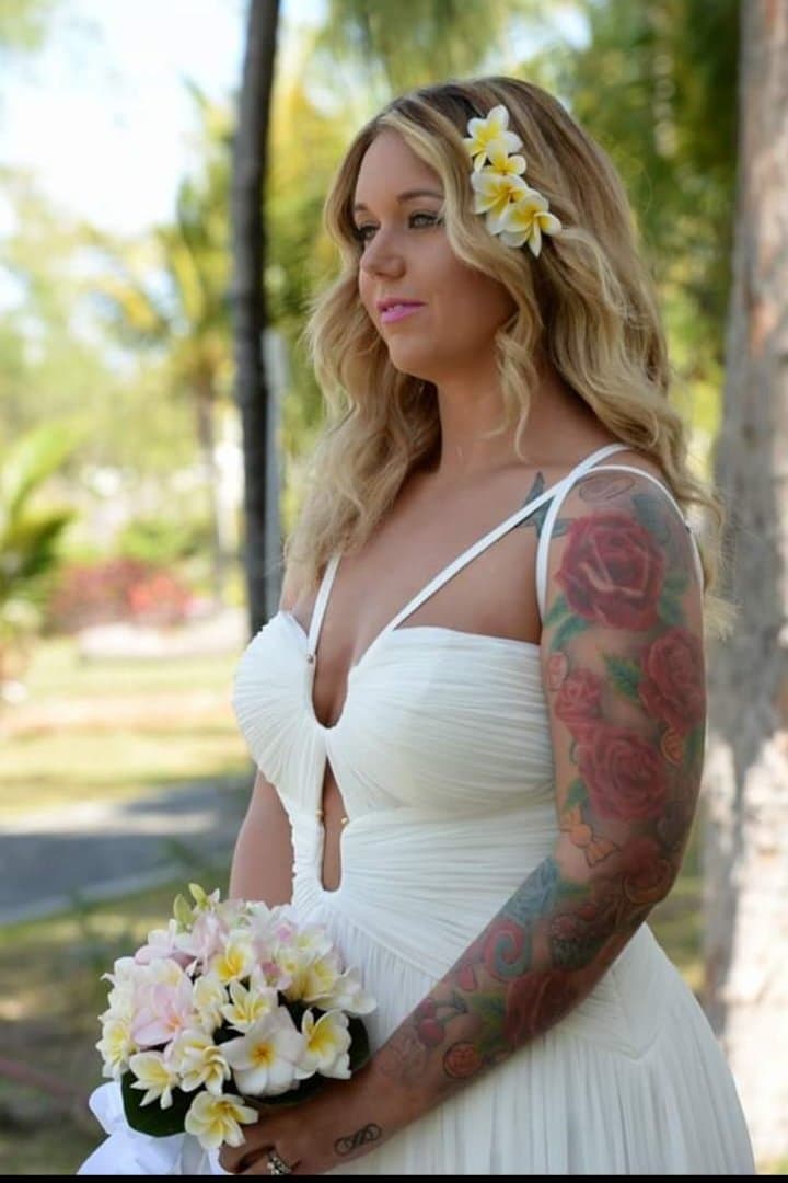 A bride holding a bouquet of frangipani, flowers in her hair