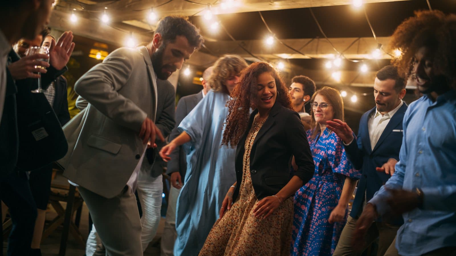 Guests dancing under festoon lights at an evening party