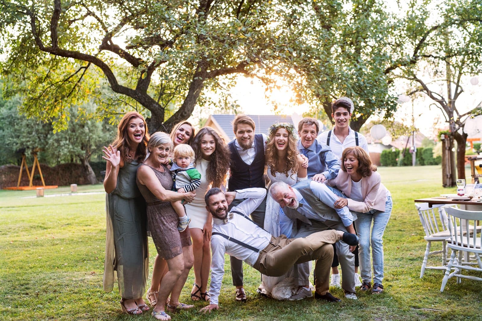 Three generations of a family piled together, laughing, at a garden reception