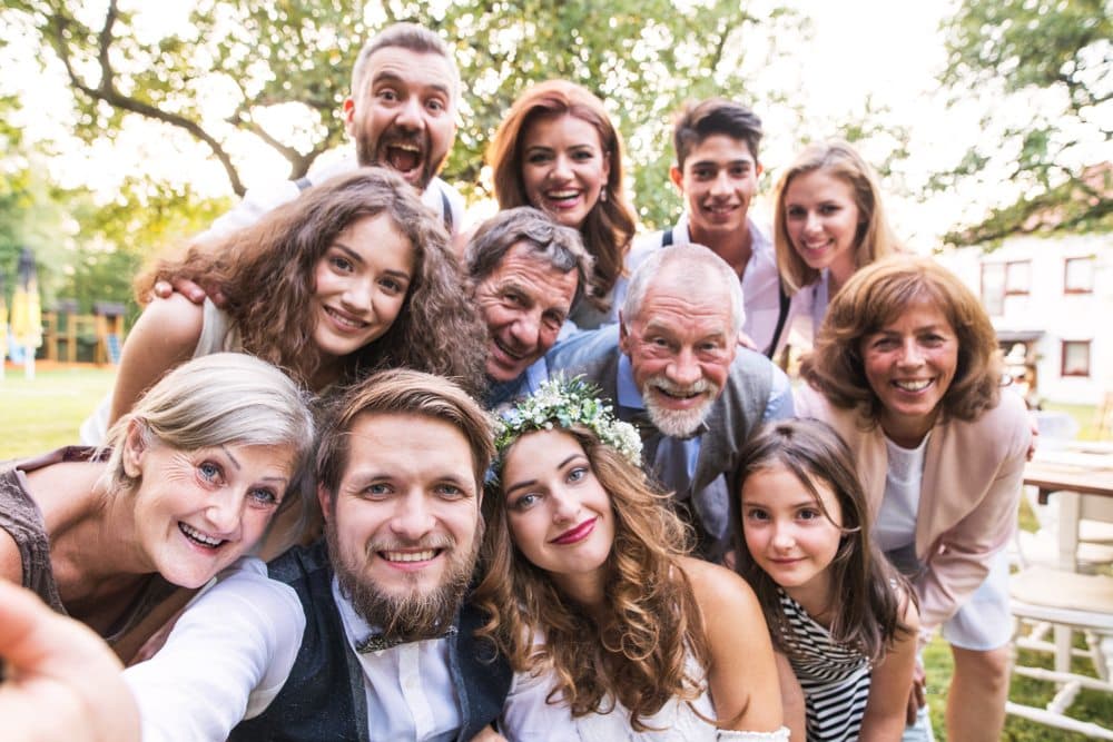 A crowd of wedding guests leaning in together for a group selfie