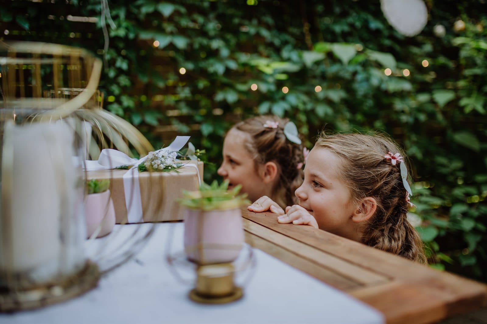 Two young flower girls peeking over the edge of the gift table